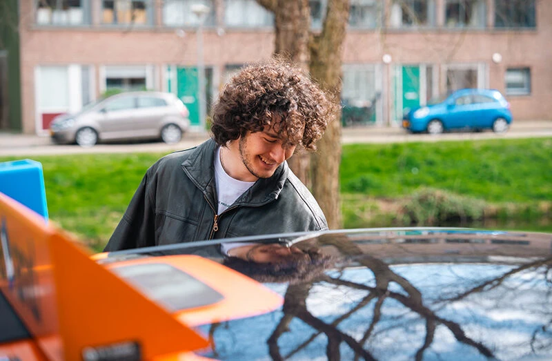 Leerling controleert de auto vóór vertrek tijdens een rijles bij Rijschool Caland in Amsterdam, met aandacht voor voertuig en omgeving voor een veilige start.